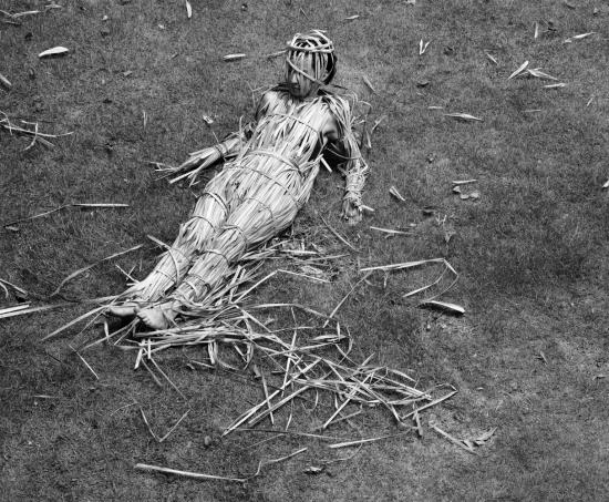 Fotografía en blanco y negro de una mujer con su cuerpo cubierto por paja